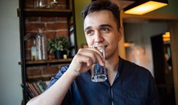 Jeune homme buvant un verre d'eau du robinet