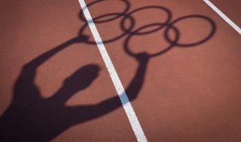 Piste athlétisme avec ombre d'un sportif tenant les anneaux olympiques