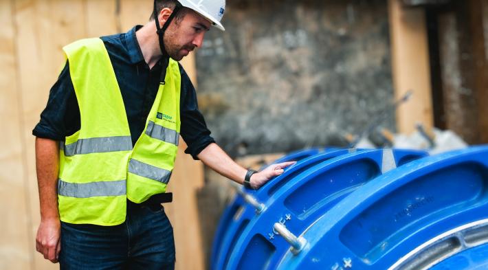 Photo d'un agent du SEDIF penché sur une canalisation