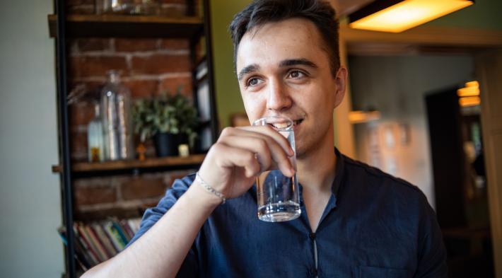 Jeune homme buvant un verre d'eau du robinet