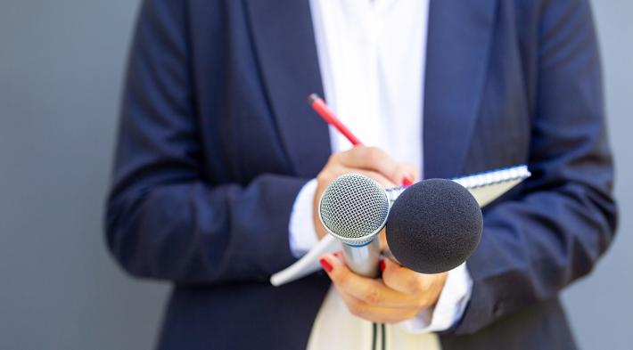 Journaliste tenant des micros et un bloc notes dans ses mains