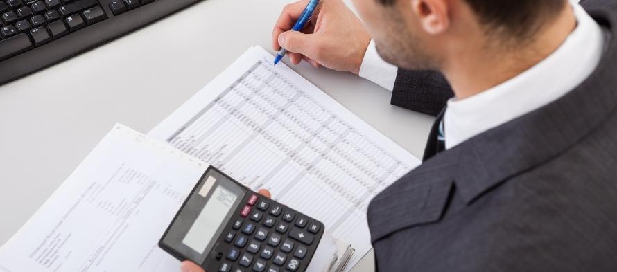 Homme tenant une calculatrice et un stylo